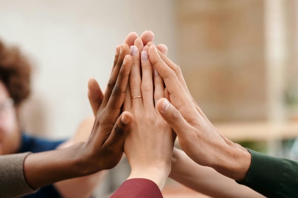 Image of volunteers with hands together during a school fundraiser ideas event